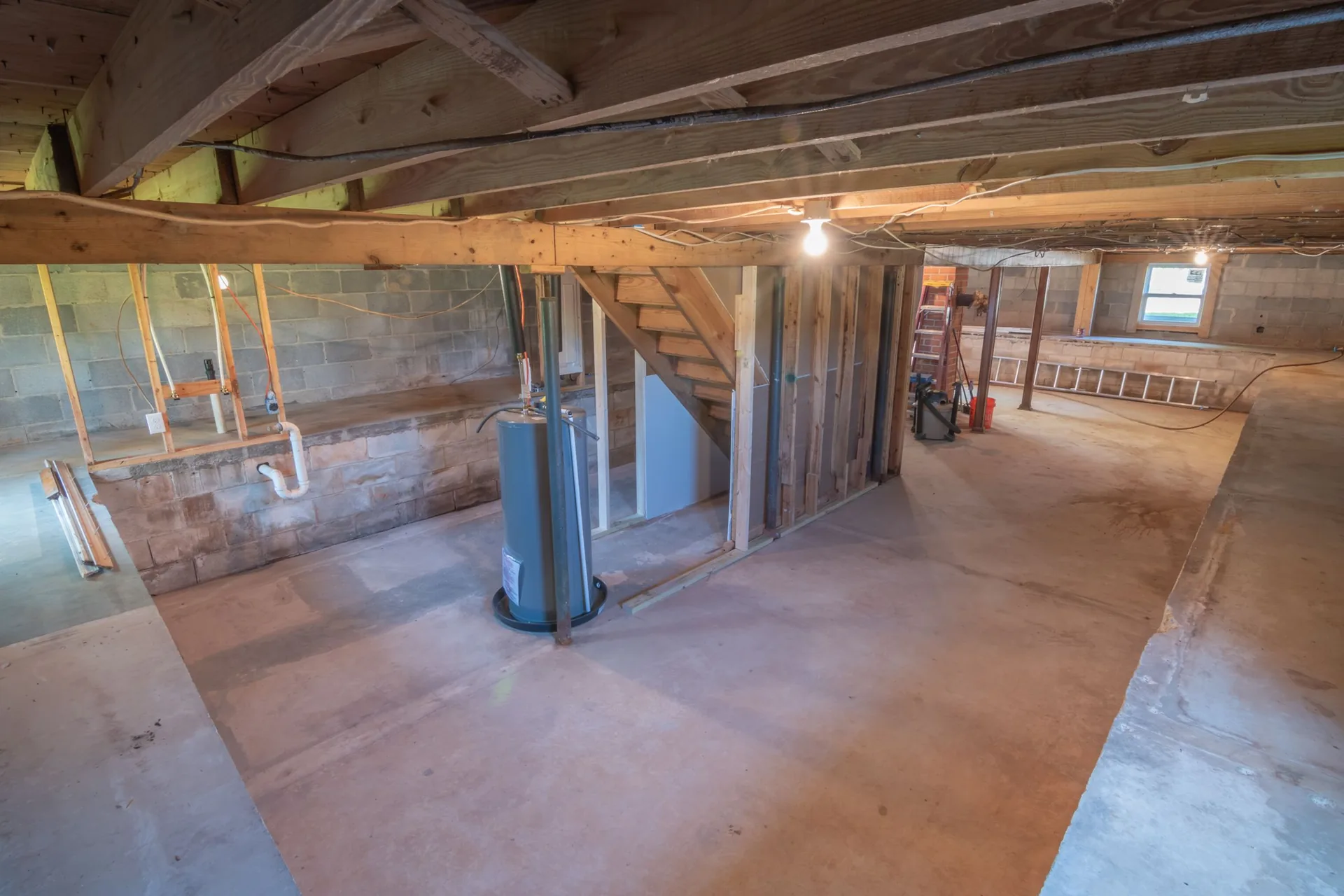 An unfinished basement with exposed plumbing along the foundation wall